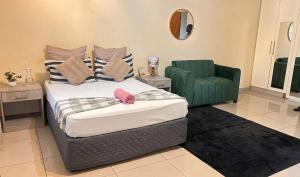 a bedroom with a bed and a green chair at Zak Guest House in Manzini