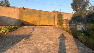 a shadow of a pole on a brick road at Zak Guest House in Manzini