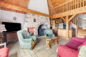 a living room with a stone fireplace and two chairs at Gîte Le Panorama in Rentières