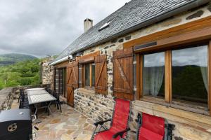 a stone house with red chairs and a table on a patio at Gîte Le Panorama in Rentières