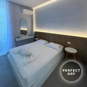 a bedroom with a white bed with a stool next to it at Perfect Day Luxury Residences in Palasë