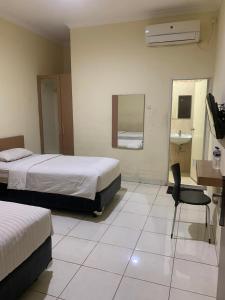 a hotel room with two beds and a desk and a chair at Marina Jampea Hotel in Makassar +19 photos