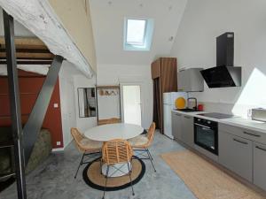 a kitchen with a table and chairs in a room at Charmant T2 - 4 couchages à 15mn de la mer in Merlevenez