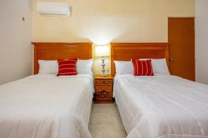 two beds in a room with two red pillows at Amplia Habitación Doble 7, Alberca, Gym y Terraza in Mérida +28 photos
