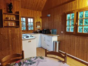 a kitchen with wooden walls and white counters and a table at La maison bleue in Saint-André-dʼHébertot