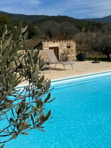 a blue swimming pool in front of a stone building at Mas Bastide st Victor à 5 mn de Lourmarin in Puyvert
