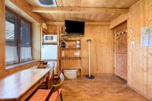 a dining room with a table and a tv in a cabin at Petit chalet Chez Gaston in Saint-François-Longchamp