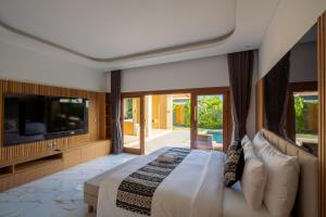 a bedroom with a large bed and a television at Suralaya Villas in Ubud