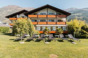 a building with chairs and tables in front of it at Residence Gold Rain in Coldrano