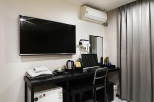 a hotel room with a desk with a television on the wall at Selene Hotel in Seoul