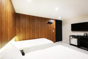 a bedroom with two beds and a flat screen tv at Selene Hotel in Seoul