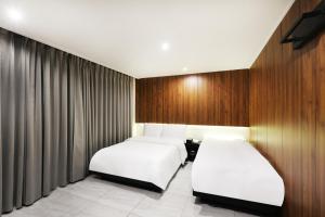 two beds in a room with wooden walls and curtains at Selene Hotel in Seoul