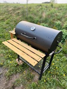 a grill sitting on a bench in a field at Domek z jacuzzi Wypoczynek Pod Lipami in Wólka