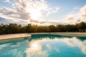 a pool of blue water with trees in the background at Agriturismo Caranna in Torre Lapillo