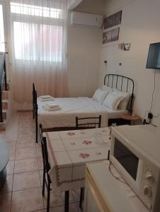 a room with two beds and a table and a tv at Studio Panagiota in Kavála