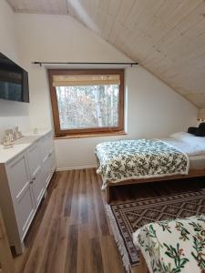 a bedroom with two beds and a window at Dom całoroczny Leśny Czar balia, sauna na 12 osób in Raków