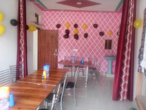 a dining room with two tables and a pink wall at Hotel shiva in Sar
