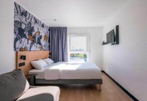 a hotel room with a bed and a chair at B&B HOTEL Bayeux in Bayeux
