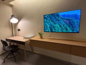 a room with a desk and a television on a wall at Brassalova Signature Stay in Port Dickson