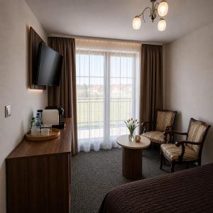 a hotel room with a bed and a television at Pluma in Grzybowo