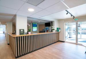 an office lobby with a wooden reception counter and a desk at B&B HOTEL Bayeux in Bayeux