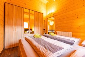 two beds in a room with wooden walls at Bungalows am Senftenberger See in Großkoschen