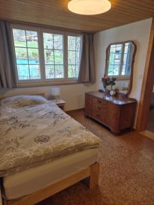 a bedroom with a bed and a dresser and a mirror at Nenis Hüsli in Diesbach