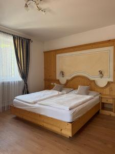a bedroom with a large bed with a wooden headboard at Garni Rika in Parcines