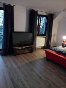 ein Wohnzimmer mit einem Flachbild-TV und einem roten Sofa in der Unterkunft Pod Zachrypniętym Kogutem in Glewo