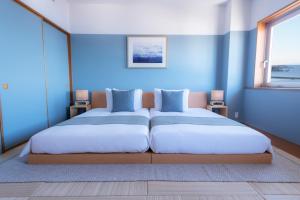 a blue bedroom with two beds and two windows at Hayama Umino Hotel in Hayama