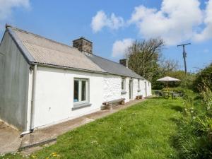 an old white building with a grass yard next to it at Rhos Y Clegyrn in Goodwick