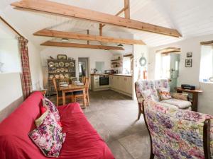 a living room with a red couch and a kitchen at Rhos Y Clegyrn in Goodwick