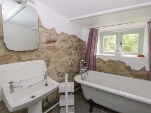 a bathroom with a tub and a sink and a mirror at Rhos Y Clegyrn in Goodwick