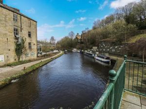 a river with boats in it next to a building at Green Route Apartment in Todmorden