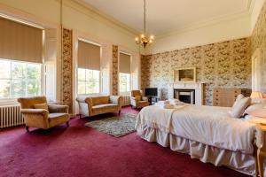 a bedroom with a large bed and a fireplace at Cheviot Manor in Wooler