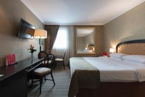 ソフィアにあるRamada by Wyndham Sofia City Centerの大きなベッドとデスクが備わるホテルルームです。