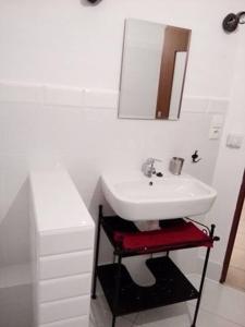 W białej łazience znajduje się umywalka i lustro. w obiekcie Pod Zachrypniętym Kogutem w mieście Glewo