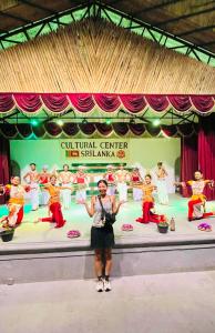 a woman standing in front of a stage with dancers at Horizon Resort & Hostel Sigiriya in Sigiriya