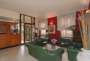 una sala de estar con muebles de cuero verde y paredes rojas. en Hotel Regina, en Lido di Camaiore