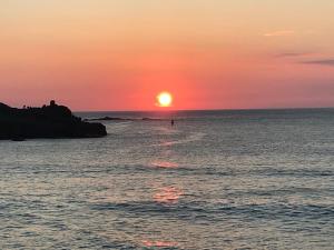 a sunset over the ocean with a person in the water at Allys cute Campervan in Carbis Bay