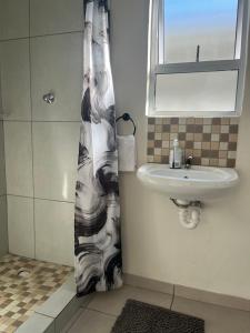 a bathroom with a sink and a shower curtain at Relaxa Sleep & Go - Self Catering Accommodation in Cape Town +12 photos