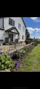 a house with benches and flowers in front of it at Lucy Cross Guest House in Lucy Cross