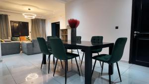 ein Esszimmer mit einem schwarzen Tisch und grünen Stühlen in der Unterkunft Résidence EBENZ in Jaunde