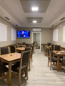 a dining room with tables and chairs and a flat screen tv at Hotel del Mar in Shëngjin