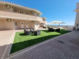 a building with a lawn with tables and an umbrella at ALDIVA ROOMS in Torvaianica