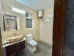 a bathroom with a toilet and a sink and a window at Blooming Inn in Gurgaon