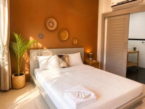 a bedroom with a large white bed with orange walls at jungle pad accomodation in Rawai Beach