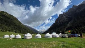 a group of tents in a field with mountains at Emin Sky Camp in Mineralʼnyy Istochnik Altyn-Arasan