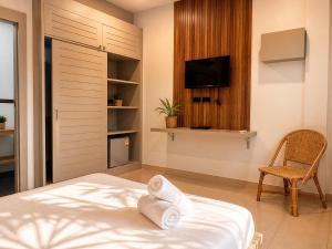 a bedroom with a bed and a tv and a chair at jungle pad accomodation in Rawai Beach +12 photos