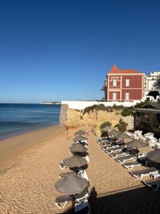 a row of beach chairs and umbrellas on a beach at T2 A 150 m de la plage in Armação de Pêra